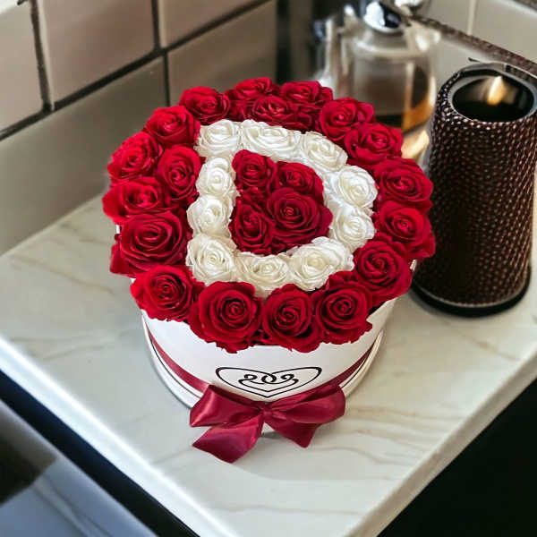 Red and white roses arranged in a round hat box with a ribbon bow
