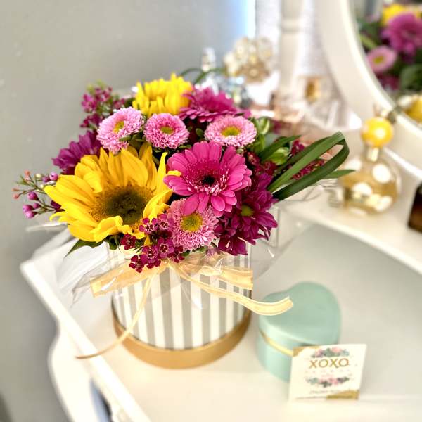 Bright mixed bouquet in a striped hatbox with a ribbon.