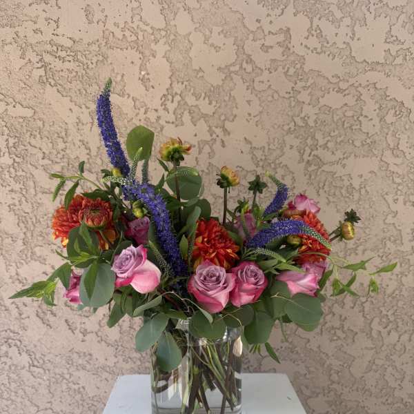Mixed pink and orange flowers arranged in a clear glass vase