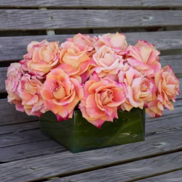 Pink and peach roses arranged in a green square vase