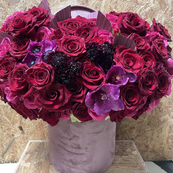 Bouquet of deep pink and purple roses in a pink velvet vase