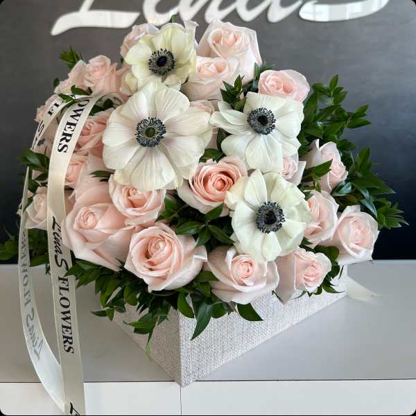 Bouquet of pale pink roses and white anemones in a square box