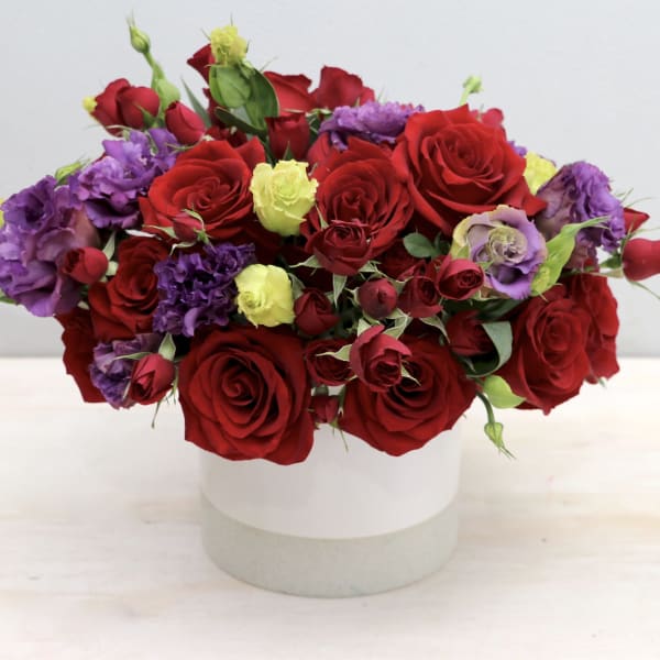 Bouquet of red and purple roses in a white round box