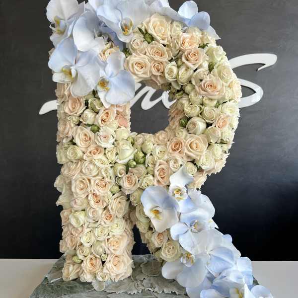 Large floral letter R covered in cream roses and white orchids
