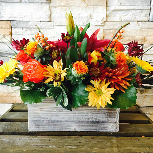 Mixed bouquet in a white wooden box with orange, yellow, and red flowers