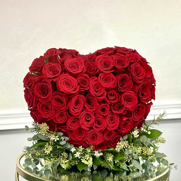 Heart-shaped arrangement of red roses with white filler flowers