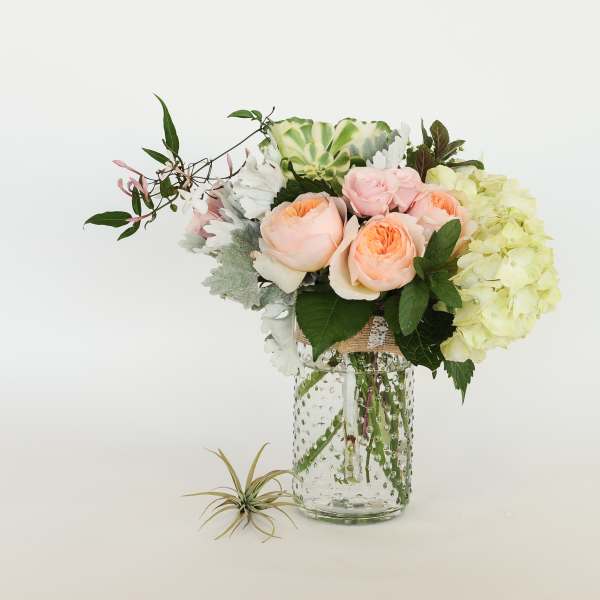 Bouquet of peach roses and pale hydrangeas in a glass vase