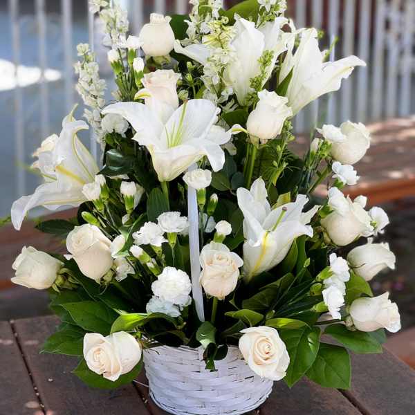 White roses and lilies arranged in a white basket