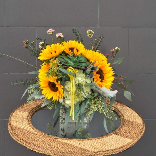Sunflower bouquet with pale hydrangea and eucalyptus in a glass vase