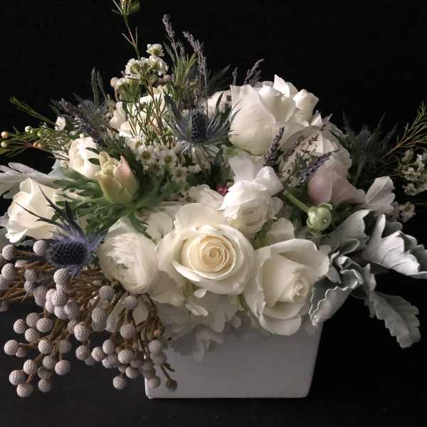 White rose arrangement in a white rectangular vase with lavender accents