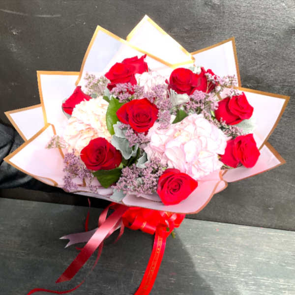 Bouquet of red and pale pink roses wrapped in white paper