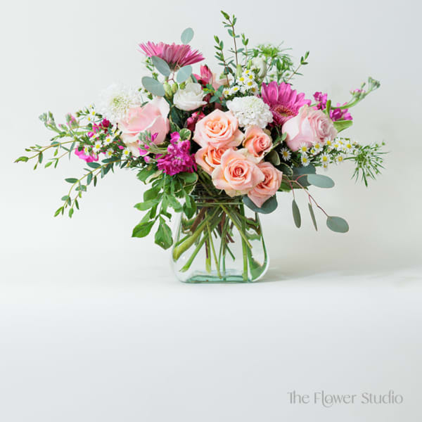 Pink and peach roses in a clear glass vase with mixed blooms