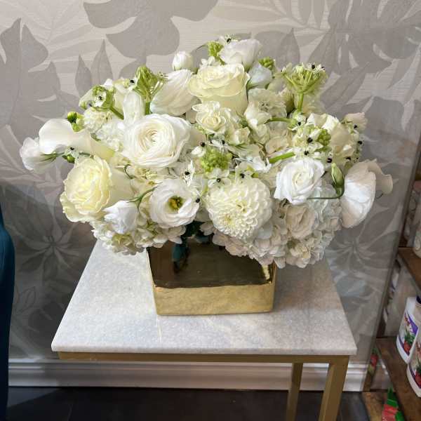 White floral arrangement in a gold square vase