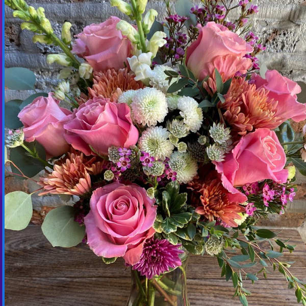 Pink roses and mixed blooms arranged in a glass vase