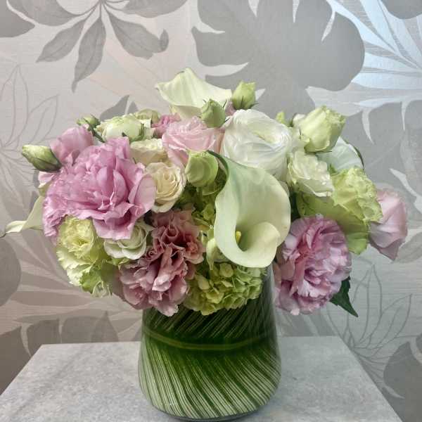 Pink and white flowers arranged in a green striped vase