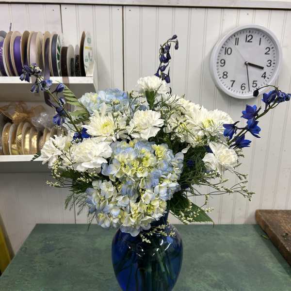 Blue and white flower arrangement in a cobalt glass vase