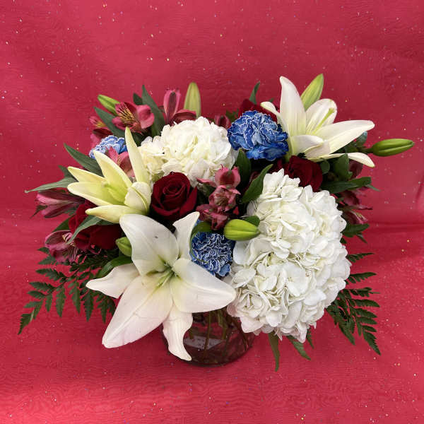 Bouquet of white lilies, red roses, and white hydrangeas in a glass vase