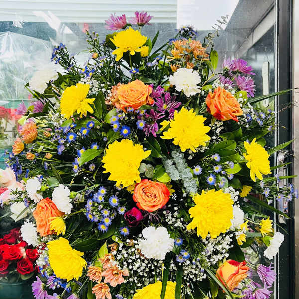 Large mixed flower standing spray with yellow, orange, white, and purple blooms
