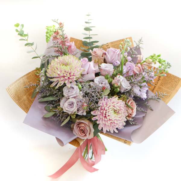 Bouquet of pastel roses and chrysanthemums wrapped in lavender paper