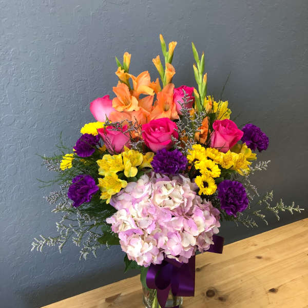 Colorful mixed bouquet in a glass vase with pink hydrangea and orange gladiolus