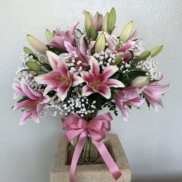 Pink lilies in a glass vase with a pink ribbon bow