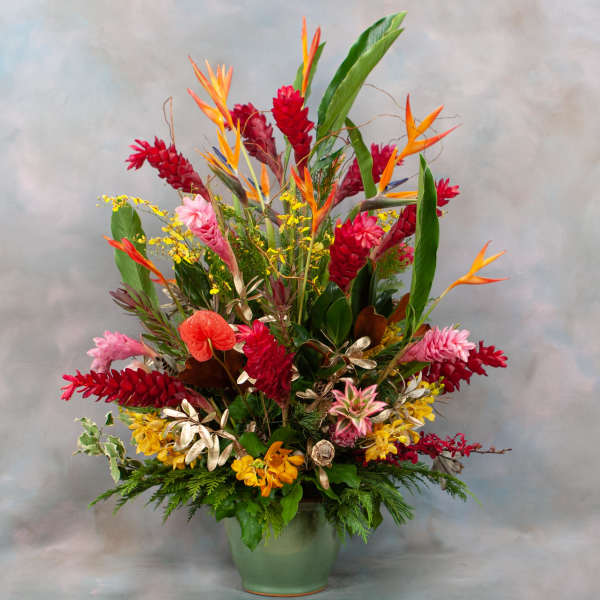 Tropical flower arrangement in a green vase with red, orange, and yellow blooms