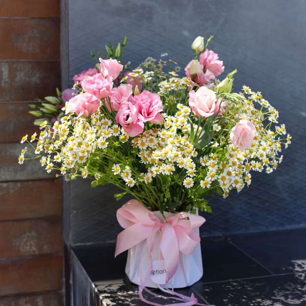 Pink roses and white daisies in a white box with a pink ribbon