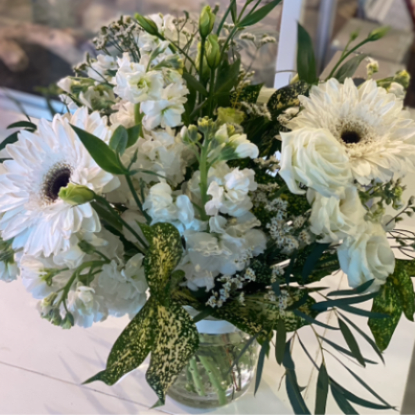 White mixed bouquet with gerbera daisies and roses in a clear vase