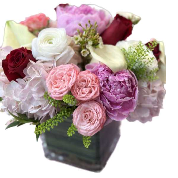 Mixed bouquet of pink, white, and burgundy flowers in a square vase