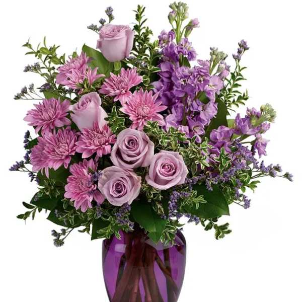 Purple roses and mixed lavender flowers in a purple glass vase