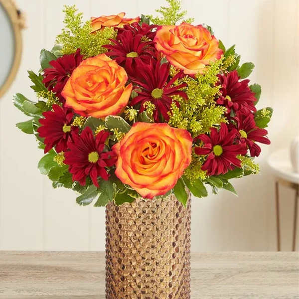 Bouquet of orange roses and burgundy daisies in a textured vase