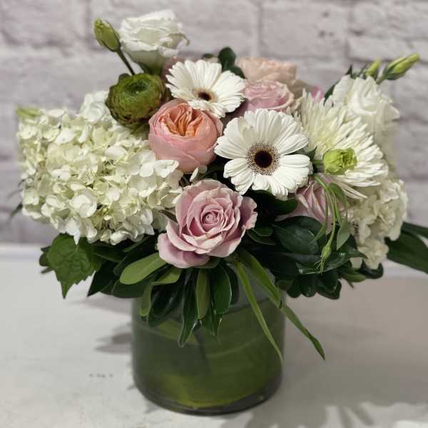Pink roses and white daisies in a green glass vase
