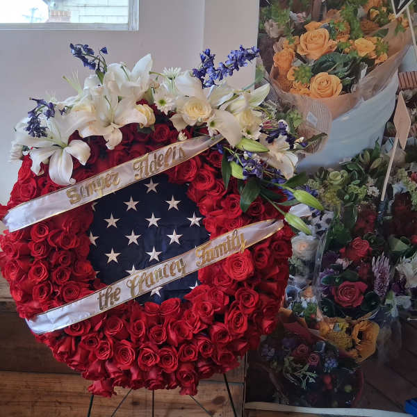 Large red rose wreath with white lilies and memorial ribbons