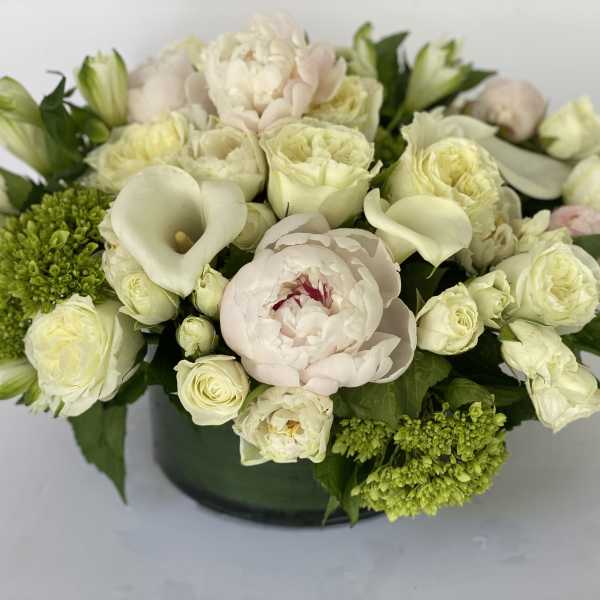 Cream and pale pink floral arrangement in a dark vase