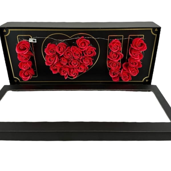 Black gift box with red roses arranged to spell I heart U inside the lid