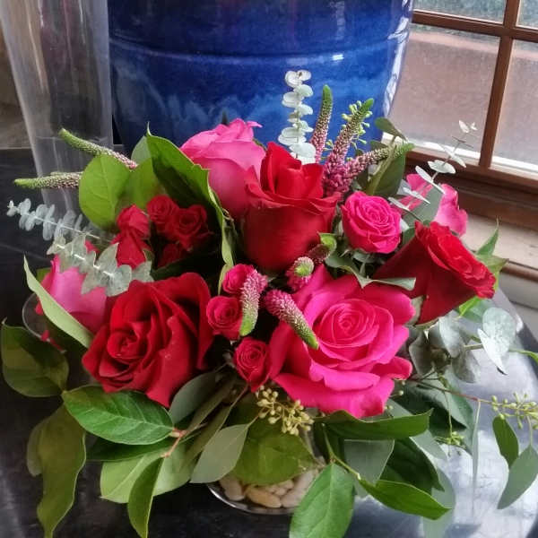 Bouquet of red and pink roses with greenery in a low vase