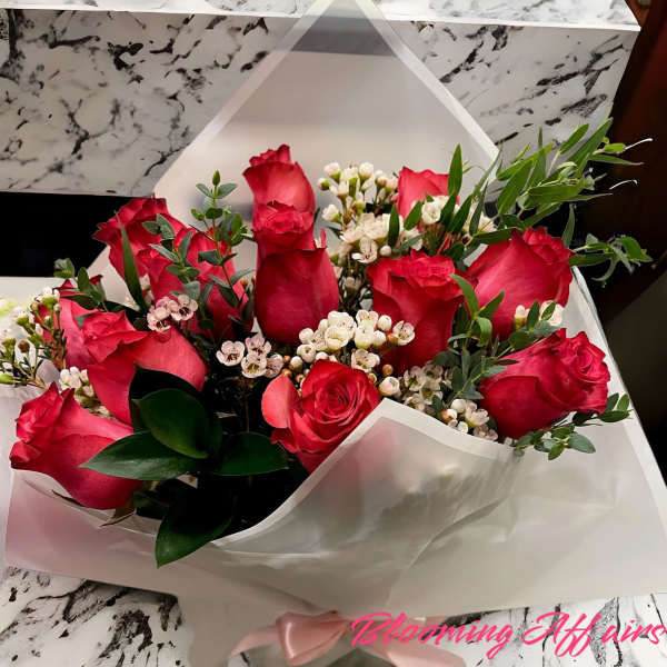 Bouquet of red roses with white filler flowers wrapped in white paper