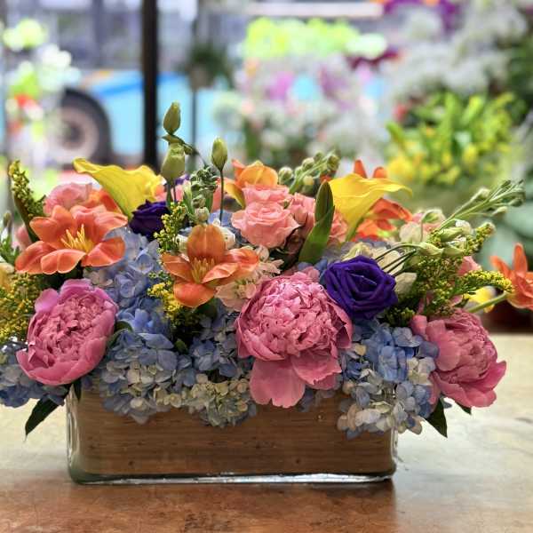 Colorful mixed flower arrangement in a rectangular glass vase