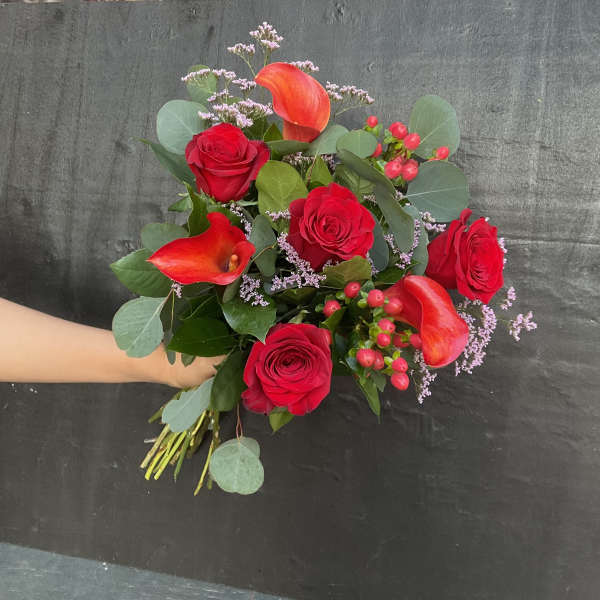 Bouquet of red roses and orange calla lilies with greenery