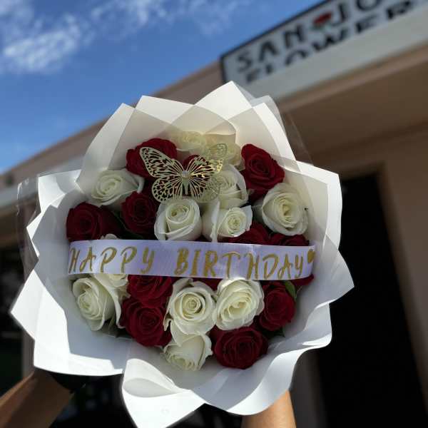Bouquet of red and white roses with a birthday ribbon and butterfly decoration