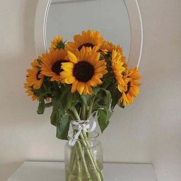 Bouquet of sunflowers in a clear glass vase with a white ribbon