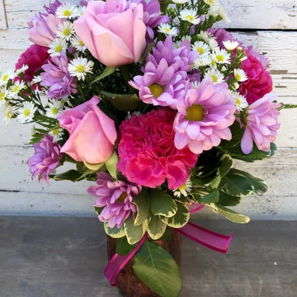 Pink roses and purple daisies in a vase with a butterfly pick