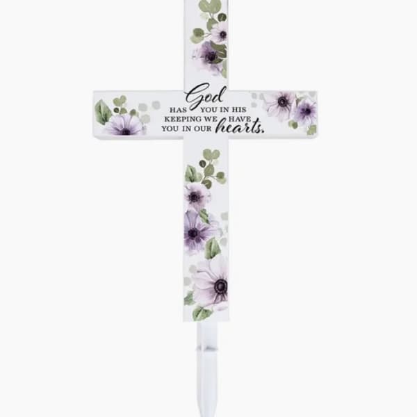 Decorative memorial cross with purple flowers and a stake