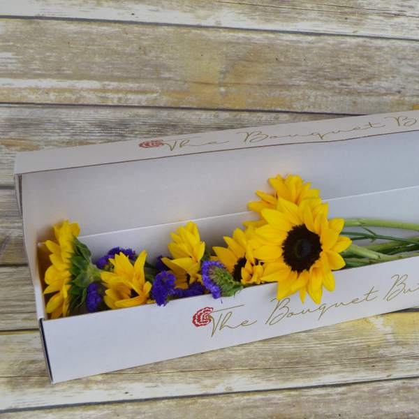 Sunflowers and purple filler flowers in a white gift box