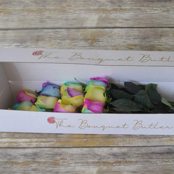 Box of multicolored roses with dark green leaves