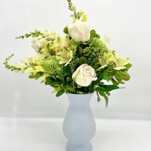 White and green floral arrangement in a pale blue vase