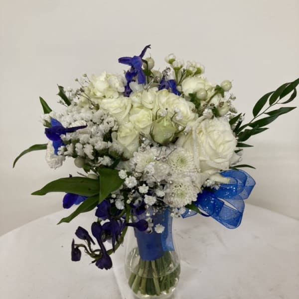 White and blue flower bouquet in a glass vase with a blue ribbon