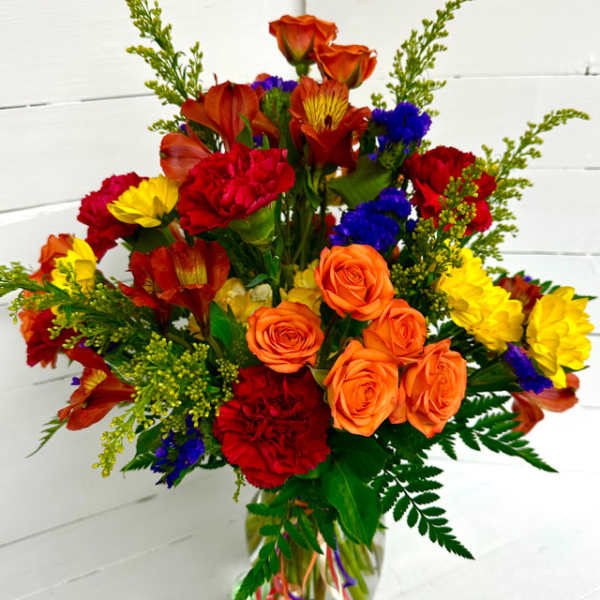 Colorful bouquet of roses, carnations, and daisies in a glass vase