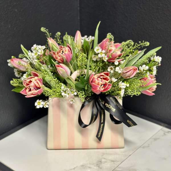 Pink tulips and white filler flowers in a striped gift box