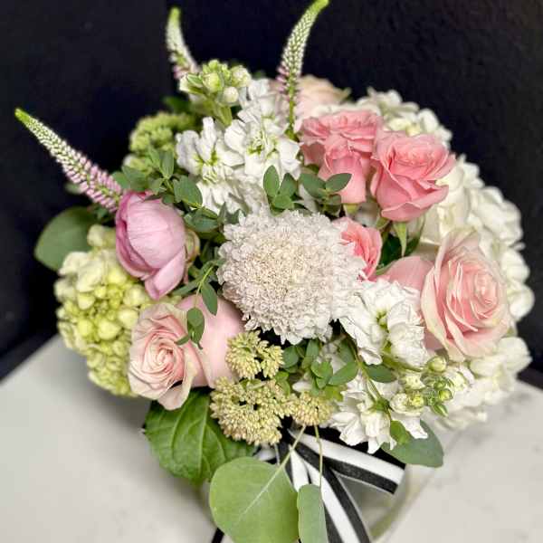 Pink and white bouquet with roses and hydrangeas tied with a striped ribbon